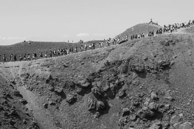 Crowd on rock against sky