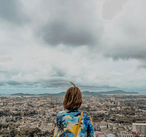 Rear view of woman looking at cityscape against sky