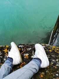 Low section of person wearing shoes while lying by lake