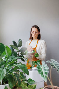 Portrait of young woman holding bouquet against wall