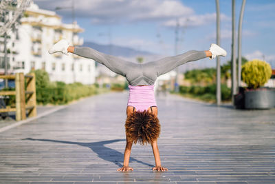 Full length of woman doing handstand on footpath