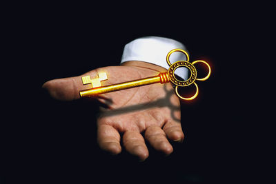 Close-up of man holding cigarette against black background