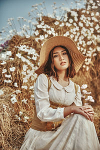 Portrait of girl wearing hat sitting against plants