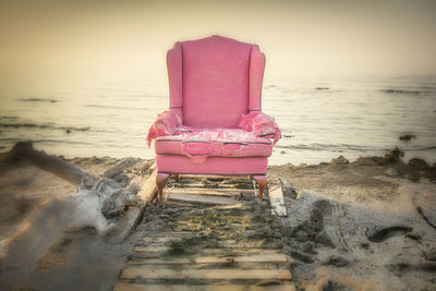 Deck chairs on shore at beach against sky