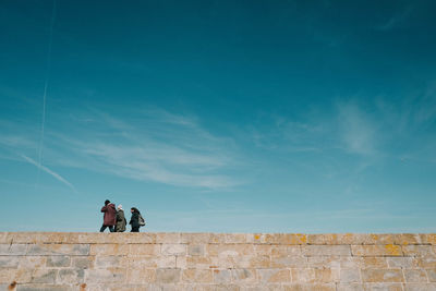 Rear view of couple on wall against sky