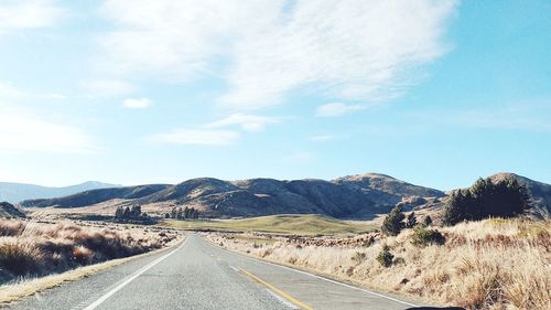 Road leading towards mountains against sky