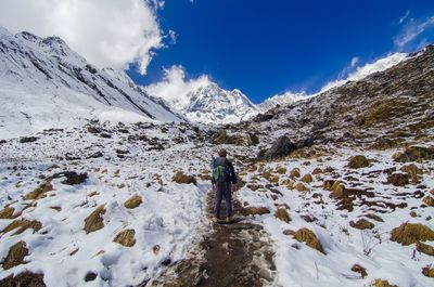 Rear view of man walking on snow covered landscape