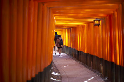 Rear view of man walking on footpath by building