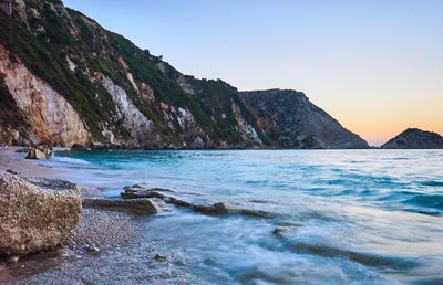 Scenic view of sea and mountains against clear sky