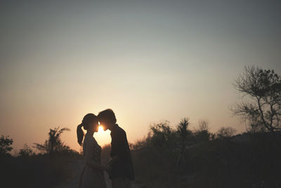 The silhouette couple with a beautiful sunset view  silhouette of hill background with tree grass