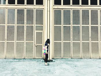 Full length of woman standing against window