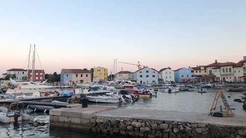 Sailboats moored at harbor against clear sky