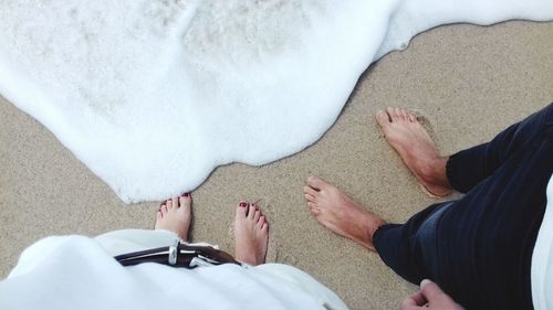 Low section of man and woman standing on beach