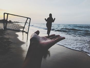 Optical illusion of woman walking on friend hand at beach