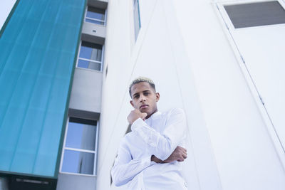 Portrait of young man standing against building