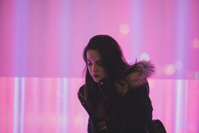 Beautiful woman standing against pink wall