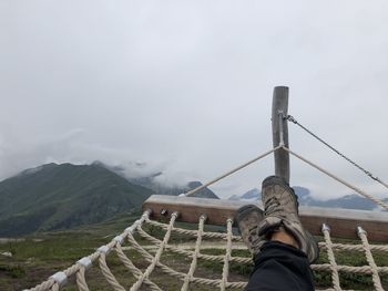 Low section of person on mountain against sky