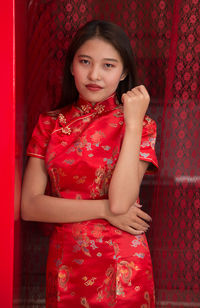 Portrait of a girl standing against red wall