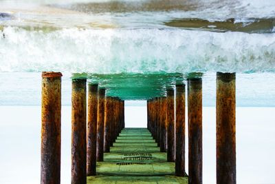 Rusted columns supporting pier at sea