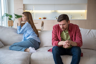 Young woman using mobile phone while sitting on sofa at home