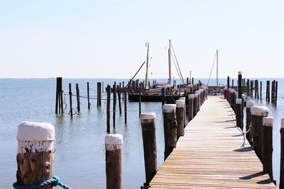 Wooden pier over sea against clear sky