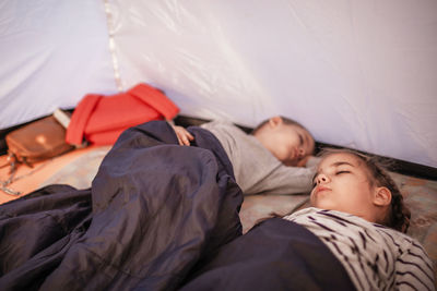 Rear view of people sleeping on bed