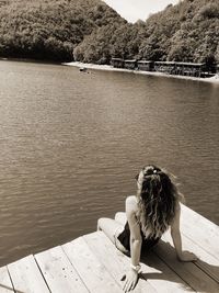 Young woman sitting on pier over lake