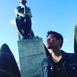 Low angle view of young man statue against blue sky