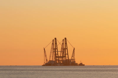 Silhouette ship in sea against clear sky during sunset