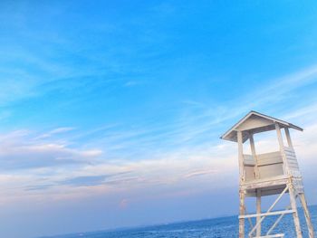 Lifeguard hut by sea against blue sky