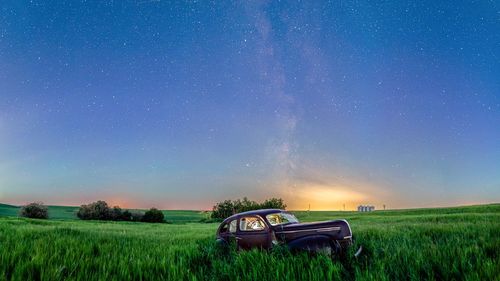 Tractor on field against sky at night