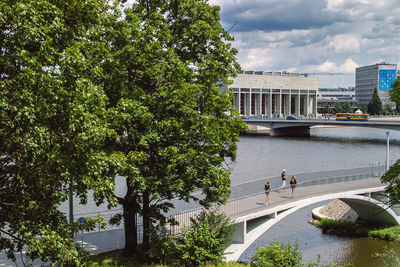 People standing by bridge in city against sky
