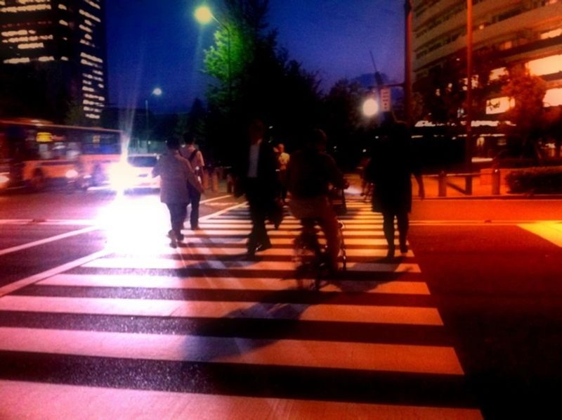 illuminated, night, city, city life, street, building exterior, men, walking, lifestyles, city street, built structure, transportation, zebra crossing, blurred motion, person, architecture, on the move, motion, large group of people