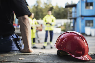 Red hardhat by carpentry teacher leaning on table outdoors