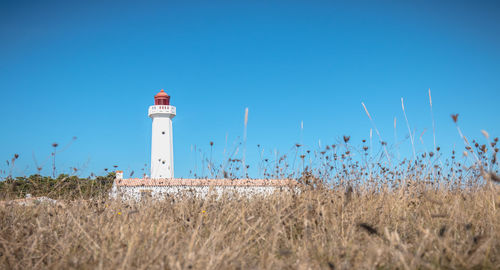 Lighthouse on field against sky