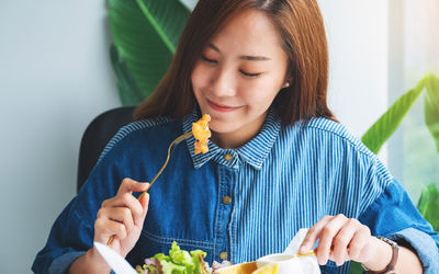 Closeup image of a beautiful asian woman eating fish and chips on table in the restaurant