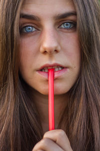 Close-up portrait of serious young woman eating candy