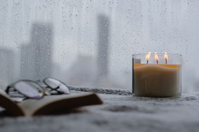 Burning aroma candle puts near by window that have rain drop in monsoon season. zen and relax.