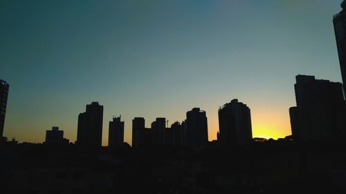 Silhouette buildings against clear sky at sunset