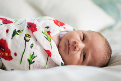 Close-up of baby girl lying on bed at home