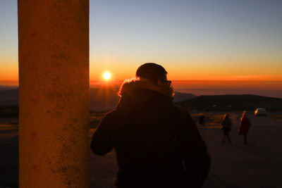 Rear view of man standing against sky during sunset