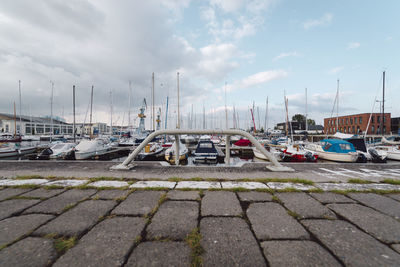 Boats moored at harbor against sky in city