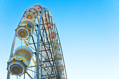 Low angle view of rollercoaster against clear blue sky