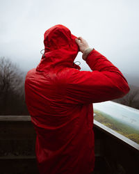 Rear view of man standing by red umbrella against sky