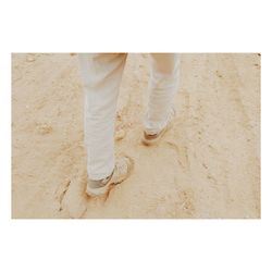 Low section of man standing on sand