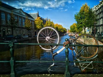 Bicycle wheel by canal against buildings in city