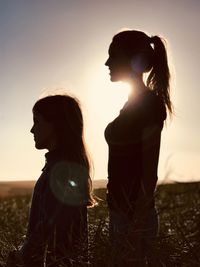 Mother and daughter standing on field against clear sky