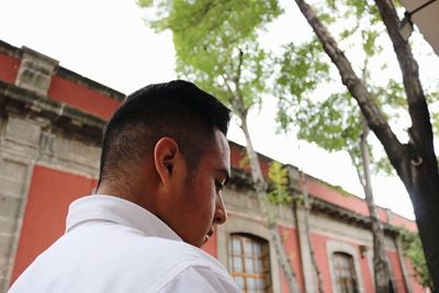 Close-up of young man standing against building