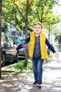Portrait of boy standing on street in city