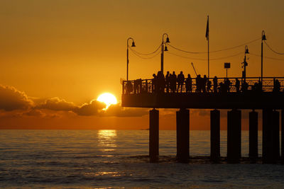 Silhouette pier on beach against sky during sunset